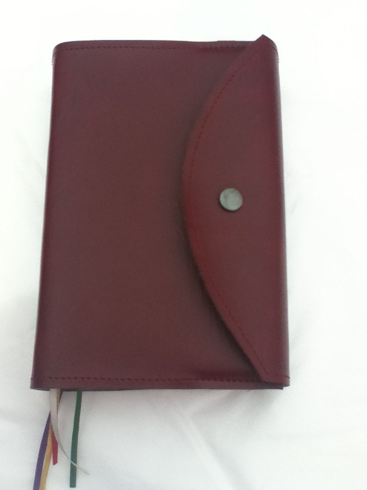 Red leatherette envelope-style missal cover shown closed from the front with a missal inside
