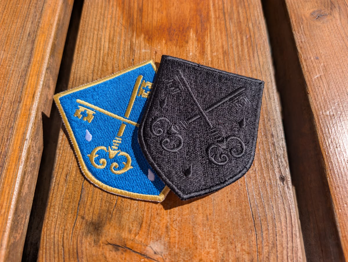 FSSP embroidered colour and black badges displayed in a fan-style arrangement on a natural wooden background in natural light
