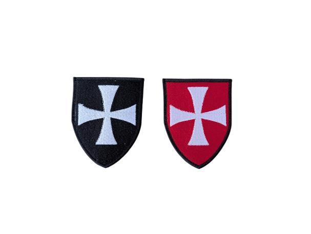 Two shield-shaped embroidered Knights Hospitaller badges displayed on a white background, with a black badge on the left and a red badge on the right, both featuring a white cross with black edging.